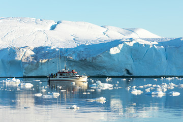 Wall Mural - small rented tourist boat in front of a massive glacier. disko bay, greenland.