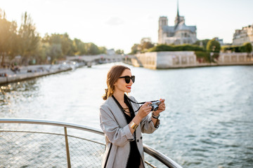 Wall Mural - Young woman tourist enjoying beautiful landscape view on the riverside with Notre-Dame cathedral from the boat during the sunset in Paris