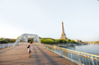 Landscape view on the river and Eiffel tower with woman walking on the footbridge during the morning light in Paris