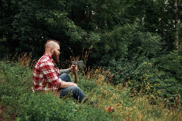 Wall Mural - Lumberjack worker sitting in forest resting after hard work