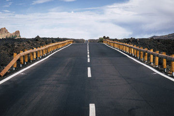 Wall Mural - long way road of asphalt with white straight line in the middle and infinite direction and travel distance concept. asphalt and mountains around for traveler and adventure concept. no cars no people
