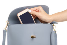 A Hand Put The Phone In The Female Blue Gray Leather Handbag On A White Background Isolation