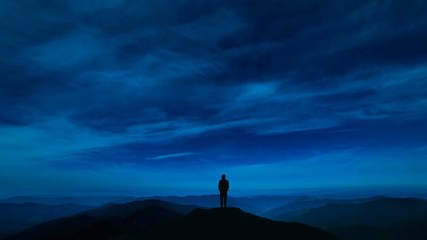 Wall Mural - The man standing on a night mountain with a cloud stream. time lapse