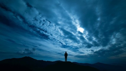 Wall Mural - The male standing on a night mountain with a cloud stream. time lapse