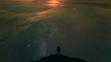 Wall Mural - The couple standing on a night mountain with a cloud stream background