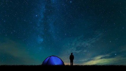 Wall Mural - The man near camping tent standing on the starry sky background. time lapse