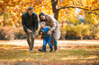© Mediteraneo - Young family having fun in the autumn park with his son.