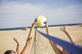 Friends playing beach volleyball on sunny day