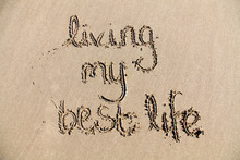 The Words 'living My Best Life' Written In Sand On A Beach