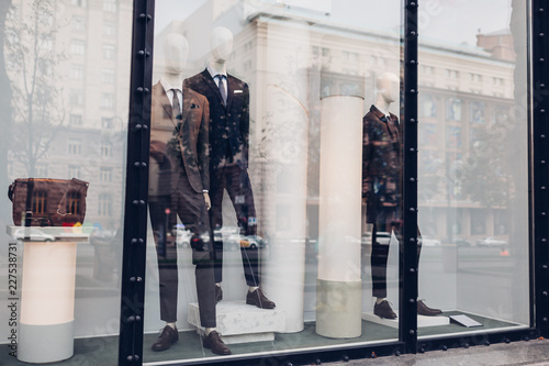 Fotomural Manikins dressed in autumn male outfits on showcase of a store in city center