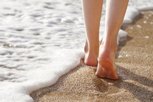 Woman Walking On A Beautiful Sandy Beach During Sunset, Feet Close Up View