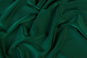 Green silk fabric background, view from above. Smooth elegant green silk or satin luxury cloth texture can use as abstract background with copy space. 