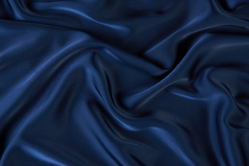 Dark blue silk fabric background, view from above. Smooth elegant blue silk or satin luxury cloth texture can use as abstract background with copy space, close-up 