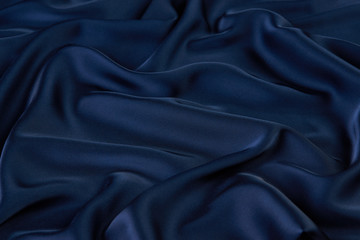 Dark blue silk fabric background, view from above. Smooth elegant blue silk or satin luxury cloth texture can use as abstract background with copy space, close-up 