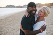 © campbell/Stocksy - Fun middle aged couple enjoying quality time on the beach at sun