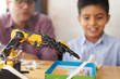© Pelle/Stocksy - Closeup of a robotic arm with boy and adult in the background