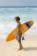 Young man with surfboard stading on the beach