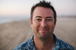 © campbell/Stocksy - Smiling, content man on beach at sunset
