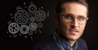 © ra2 studio - Portrait of a young businessman with rotating gears next to him on a dark background