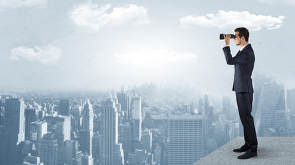 Wall Mural - businessman looking forward to a city with binoculars from skyscraper concept