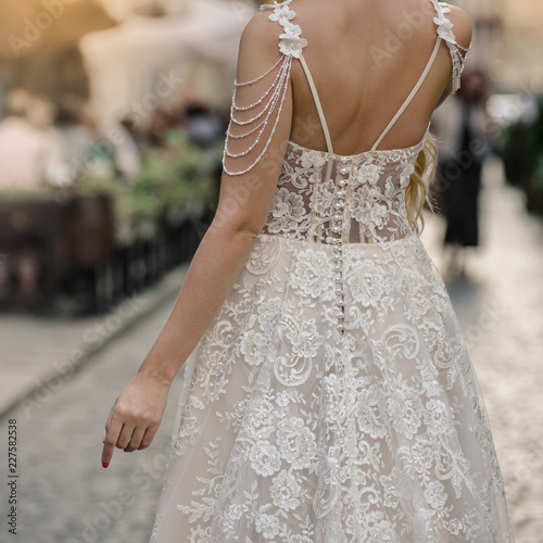 Foto Bride in white silk dress with lace standing back on city street
