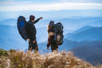 Wall Mural - the man and a woman gesturing on the cliff with a beautiful view