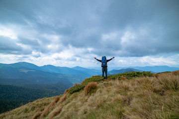 Wall Mural - the happy man standing on the mountain on the rainy clouds background