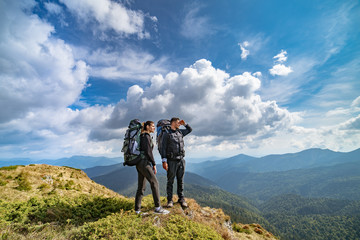 The couple on the mountain on the picturesque cloudscape background