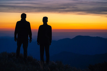 Wall Mural - the couple standing on the mountain on a sunrise background