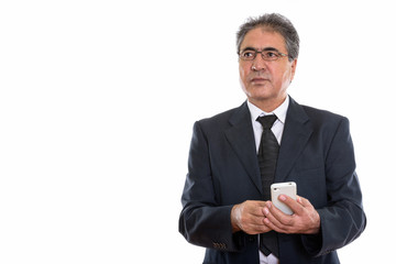 Studio shot of senior Persian businessman holding mobile phone w