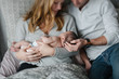 © campbell/Stocksy - Happy new family of three cuddling in the bed together at home