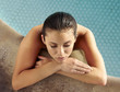 © trinettereed/Stocksy - Hispanic woman relaxing in swimming pool at luxury resort
