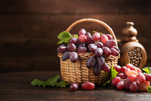 Ripe Grapes In Wicker Basket On Wooden Background.