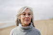 © Bonninstudio/Stocksy - Senior woman on the beach in winter.