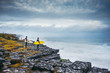 © DavidSciora/Stocksy - Surfers looking at the stormy ocean from the cliff