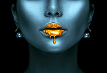 Gold Paint Drips From The Sexy Lips, Golden Liquid Drops On Beautiful Model Girl's Mouth, Creative Abstract Dark Blue Skin Makeup. Beauty Woman Face