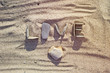 Word love made from pebbles and heart shape stone on a sandy beach