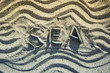 Word sea made from pebbles and wave shape on a sandy beach