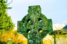 Colourful Background Of Lichen Covered Celtic Cross.