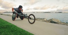 Disabled Wheelchair Athlete Pushing Racing Chair Outside At Sunset Working Out 