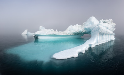 Wall Mural - panorama of a massive iceberg with a smooth underwater shelf on a foggy day. disko bay, greenland.