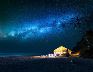 Wall Mural - beach with glowing tent at night with falling stars