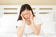 Young asian woman headache on white bed in the morning
