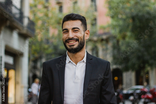 Fotomural Handsome arabic guy smiling. Successful man walking on the street