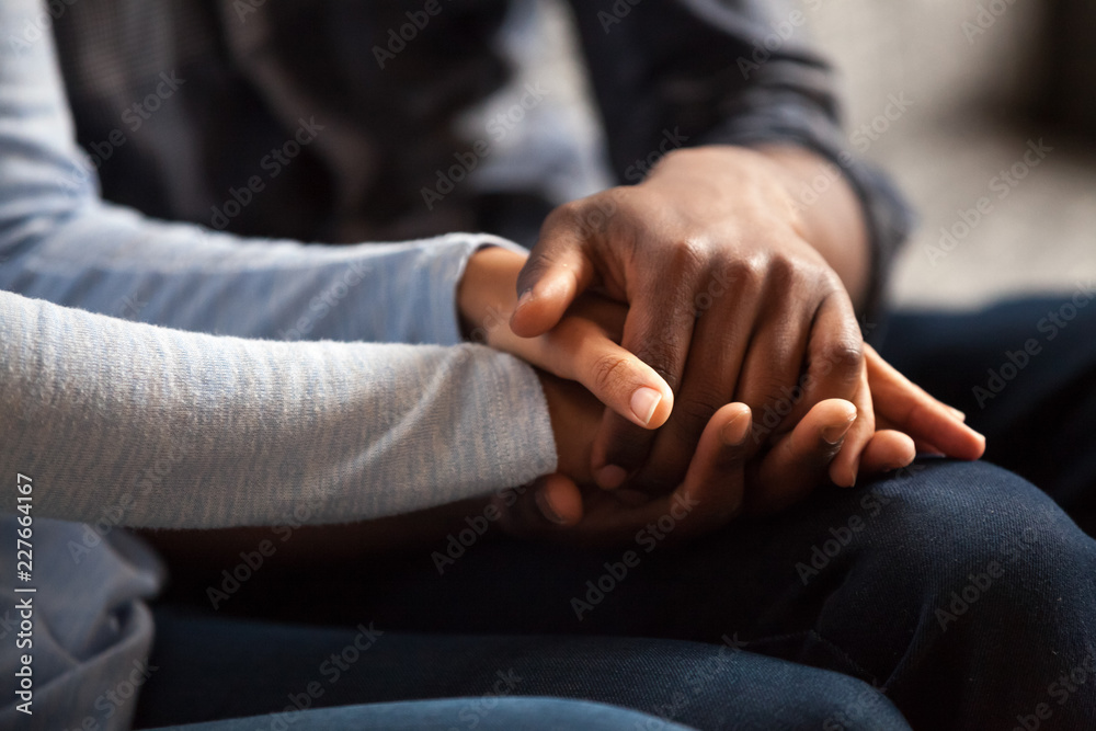 Close up black woman and man in love sitting on couch two people holding hands. Symbol sign sincere feelings, compassion, loved one, say sorry. Reliable person, trusted friend, true friendship concept - obrazy, fototapety, plakaty 