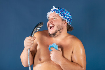 Funny fat man in blue cap sing in the shower