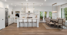 Beautiful Kitchen And Dining Room Panorama In New Luxury Home, With Pendant Lights, Dining Room Table And Chairs, Kitchen Island, And Counters