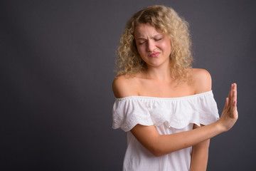 Young beautiful woman with blond curly hair against gray backgro