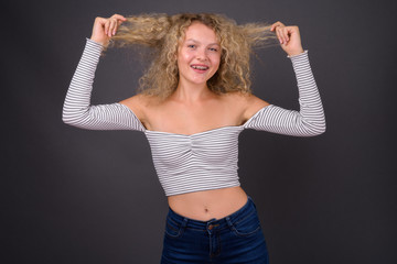 Young beautiful woman with blond curly hair against gray backgro