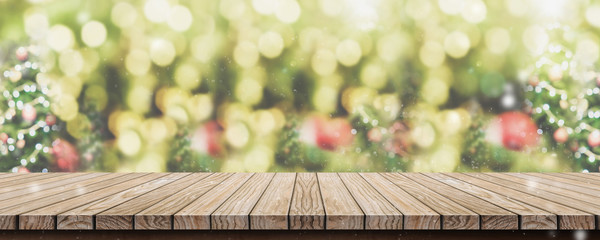 Fototapete - Empty brown wooden table top with abstract green blur christmas tree and snow fall background with bokeh light,Holiday backdrop,Mock up banner for display or montage of product.
